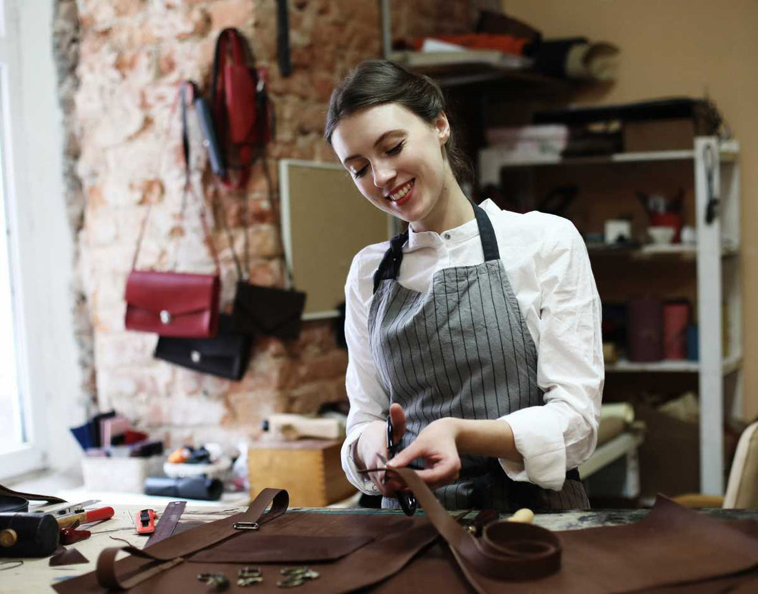 Woman sewing a leather bag using bag-making tools and materials.