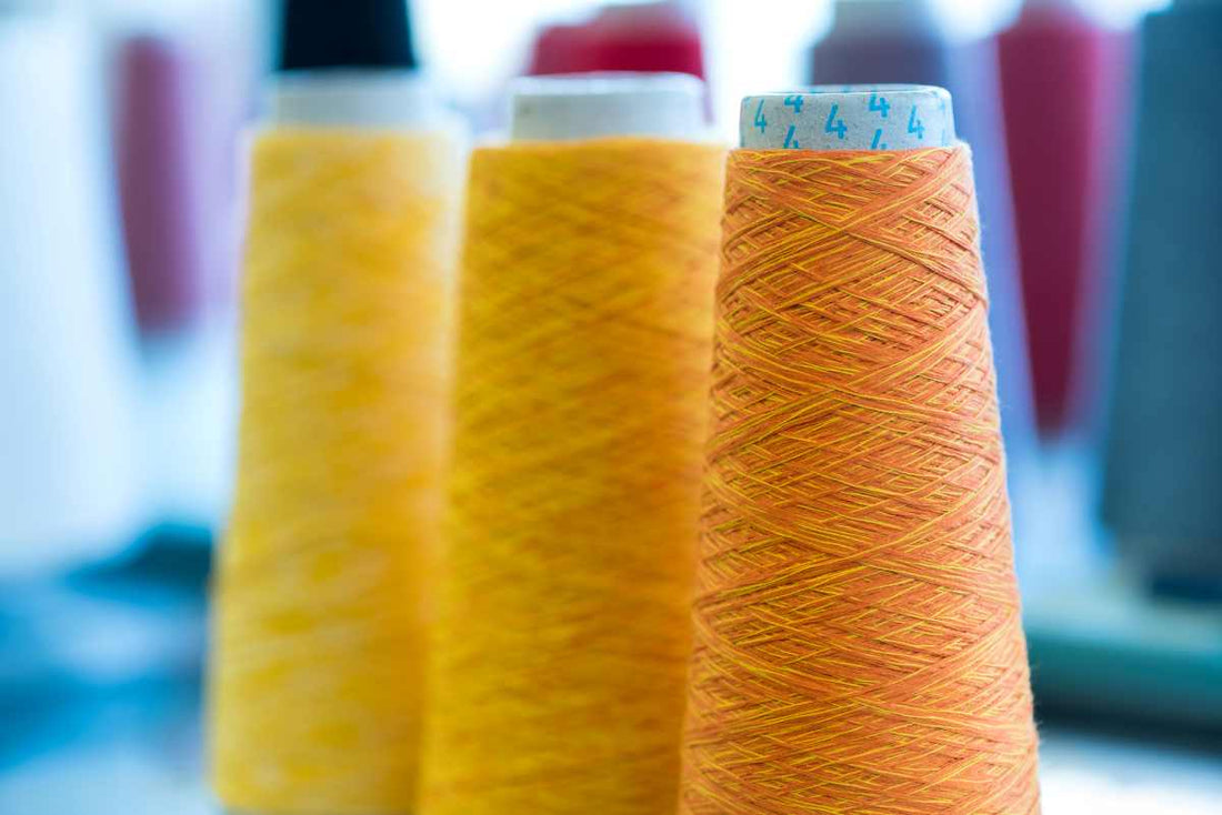 Close-up of colourful overlocking thread cones used for garment construction and seam finishing in textile and sewing projects